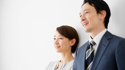 白壁を背にして立っているビジネスマンとビジネスウーマン