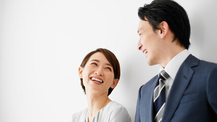 白壁を背にして立っているビジネスマンとビジネスウーマン