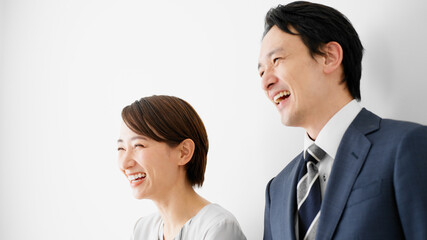 白壁を背にして立っているビジネスマンとビジネスウーマン