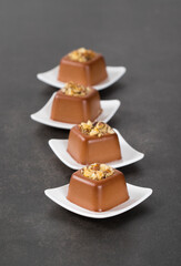 Vegan Chocolate nut cream dessert in the shape of a square savarin on a plate on a dark gray background. 