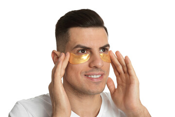 Man applying golden under eye patches on white background