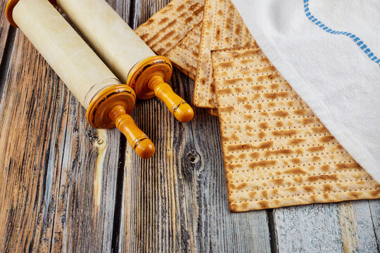 Matzah, tallit and torah on wooden background.