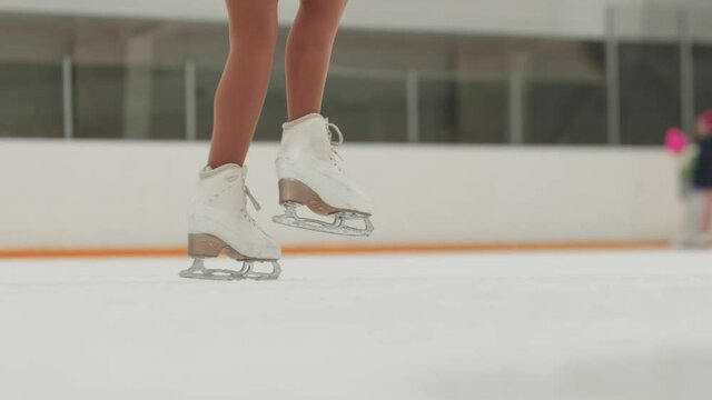 Close up on the ice skates while performing figure spinning on the ice rink