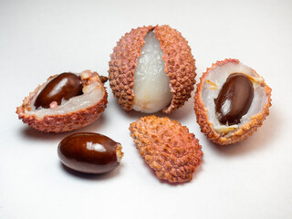 Sliced ​​lychee. Round pimply fruits. Chinese plum. Fruit peel. Peeling the lychee. Pieces of juicy fruit on a bright background.