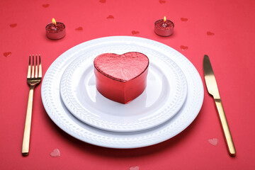 Romantic table setting, gold cutlery on the red table cloth. Valentine's day celebration