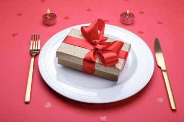 Romantic table setting, gold cutlery on the red table cloth. Valentine's day celebration
