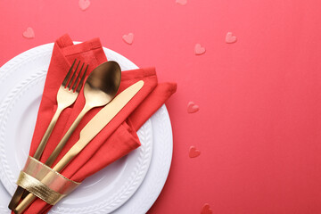 Romantic table setting, gold cutlery on the red table cloth. Valentine's day celebration