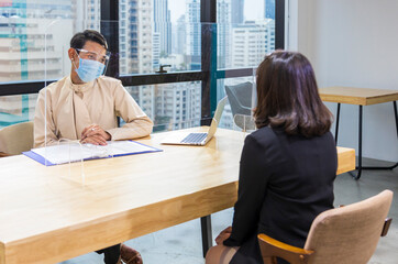 LGBTQ manager from HR department wearing facial mask is interviewing new applicant and looking at...