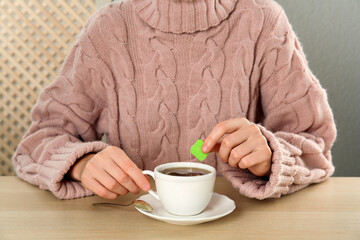 Woman with cup of tea at wooden table, closeup