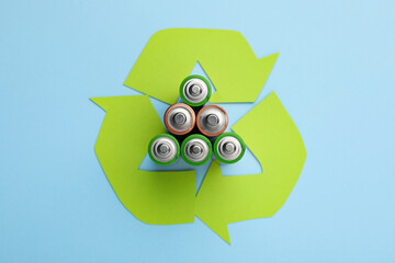 Used batteries and recycling symbol on light blue background, flat lay - obrazy, fototapety, plakaty