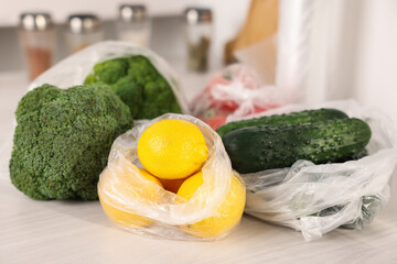 Plastic bags and fresh products on white table