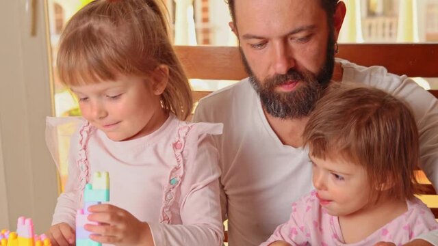 Happy girls playing constructor game with Father 