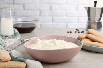 Bowl with mascarpone cream on white wooden table. Making tiramisu cake
