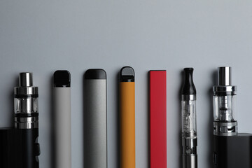 Many different electronic cigarettes on light background, flat lay