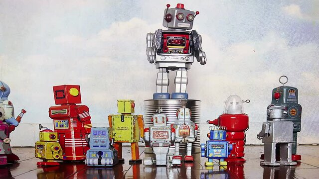 big silver robot on his soapbox speaking to a crowd of retro toy robots