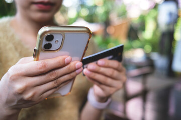 Woman hand holding credit card and smartphone for paying online using banking service. Online shopping concept