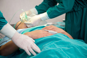 Closeup hands of doctor and assistant holding oxygen mask with patient emergency in the operation room at hospital, surgeon healing and surgery, problem of breathing, instruments medical and health.