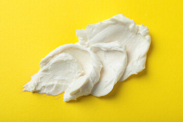 Fototapeta na wymiar Smear of delicious cream cheese on yellow background, top view