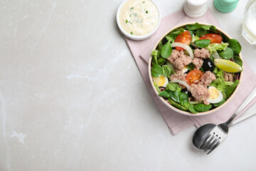 Bowl of delicious salad with canned tuna and vegetables served on light table, flat lay. Space for text