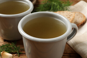 Hot delicious bouillon in cups on table, closeup