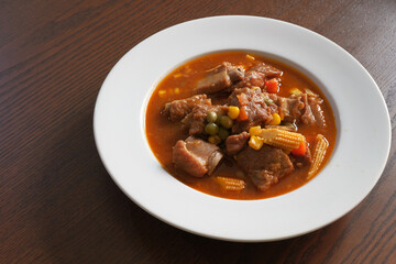 Pork ribs stew in white plate on wooden table