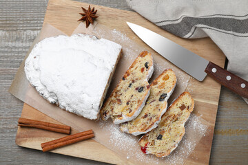 Traditional Christmas Stollen with icing sugar on wooden table, flat lay