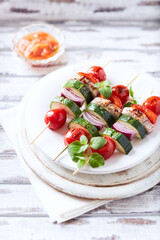 Grilled shashliks with vegetables and pork tenderloin. Bright wooden background. Close up.