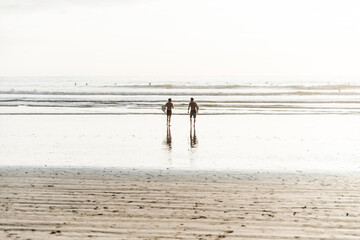 Fototapeta na wymiar Two surfers walking into the ocean in Costa Rica. 