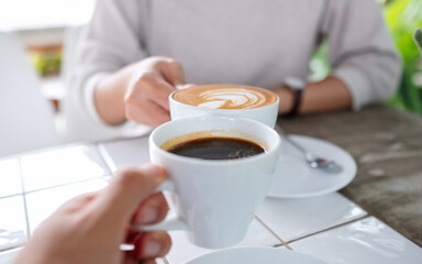 Closeup image of a couple people clinking coffee cups together in cafe