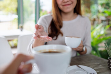 Closeup image of a couple people enjoyed talking and drinking coffee together in cafe