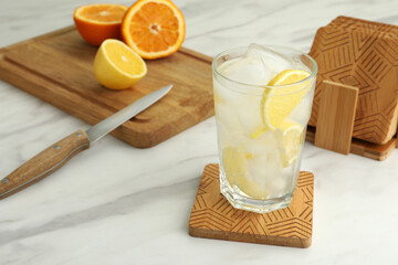 Glass of cocktail and stylish wooden cup coasters on white table - obrazy, fototapety, plakaty