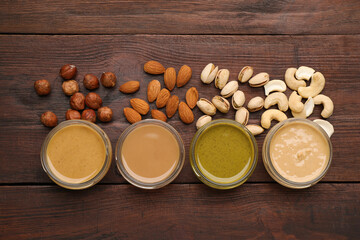 Different types of delicious nut butters and ingredients on wooden table, flat lay