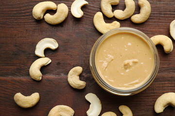 Delicious cashew butter and ingredients on wooden table, flat lay