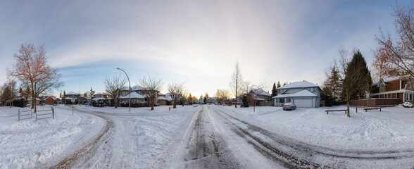 Residential Neighborhood in the Suburbs with White Snow covered road. Sunny Sunrise. Taken in...