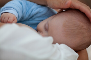 Beautiful woman breastfeeding a baby against the background of white sheets