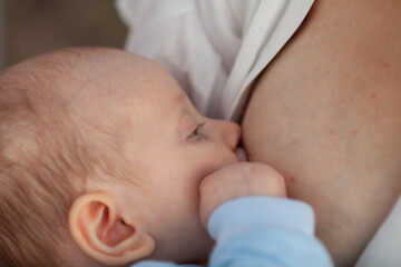Beautiful woman breastfeeding a baby against the background of white sheets