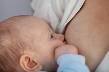 Beautiful woman breastfeeding a baby against the background of white sheets