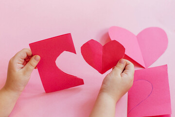 Step by step instructions. How to make a paper heart card for Valentine's Day. Creative crafts. Do it yourself. little girl cuts a heart out of paper, makes a card with her own hands 