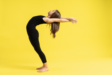 Obraz na płótnie Canvas girl gymnast studio. little gymnast trains, shows a gymnastic element. do sport. Isolated on a colored yellow background. Young girl gymnast