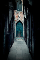 Fototapeta na wymiar Narrow alley with Teal door at the end in Italy