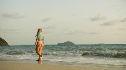 Fototapeta na wymiar Sexy woman walking alone on beach coastline and relax warm golde