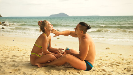 Cute loving couple each other having sun block. Woman to put sun