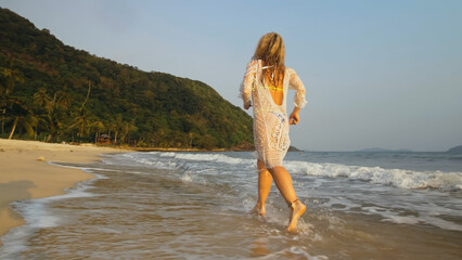 Woman in a White Tunic on the Beach, near the Sea. Blonde in Sun