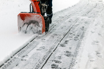 A man removes snow from sidewalks with a snow blower in winter at an electrical substation