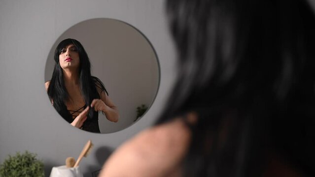 A homosexual man puts on makeup in front of a mirror. Male transgender.