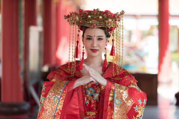 Beautiful young woman in a bright red dress and a crown of Chinese Queen posing happy Chinese new...
