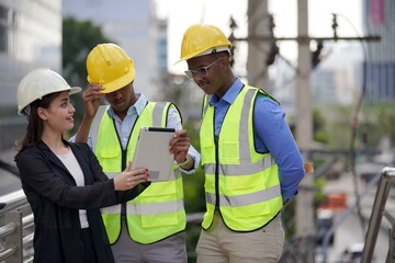 Group of young engineer in suits, and foreman in reflective vests and wearing safety helmet use tablet . Engineering and construction concept.