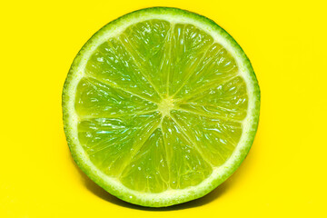 Juicy Sliced Lime, isolated on a bright yellow background, delicious citrus fruit.