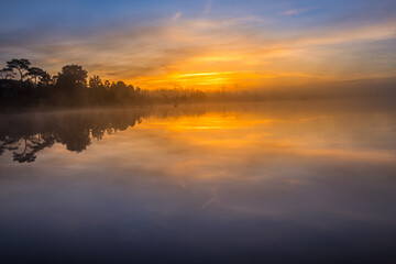 Sunrise over water with foggy at Wang Kwang Reservoir Phu Kradueng National Park, Loei province, Thailand