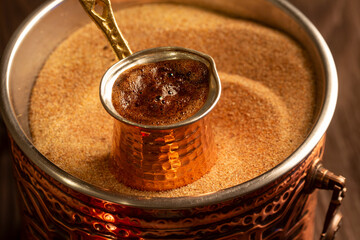 Traditional Turkish coffee with foam in cezve prepared on hot sand in authentic Turkish Copper.